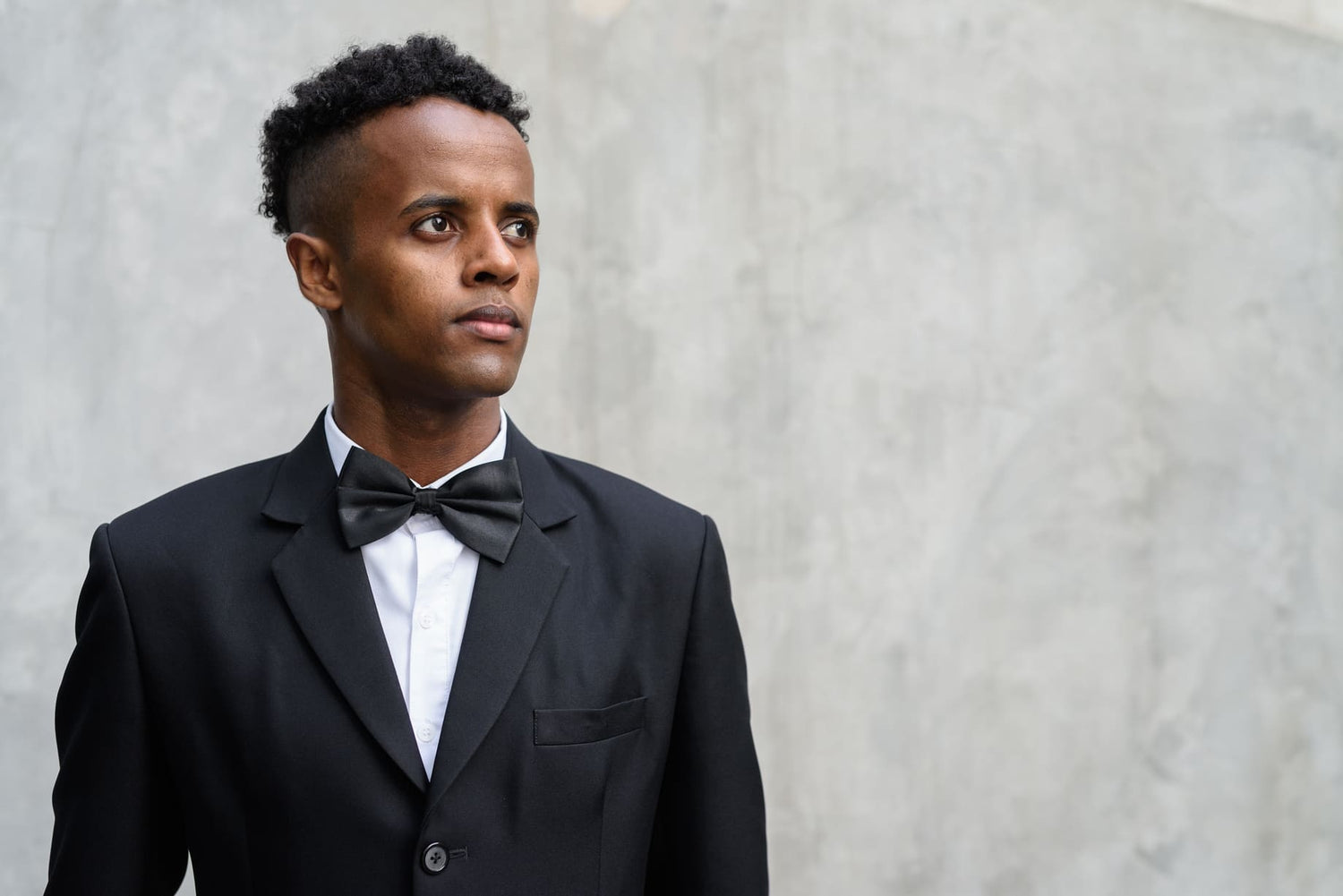 Black Tie Wedding Attire image, Young handsome African businessman wearing suit against concrete